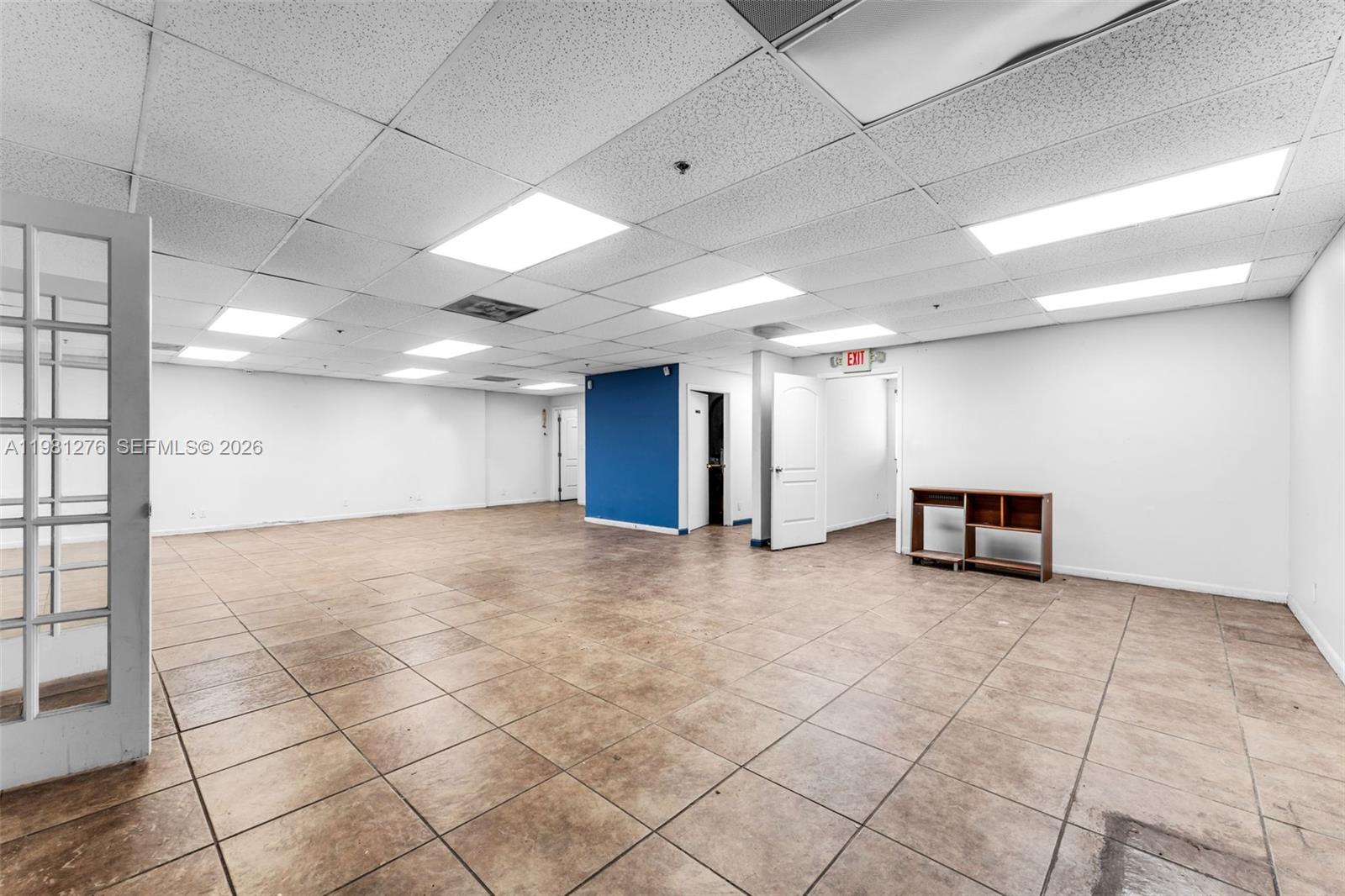 An empty office space features white walls, a drop ceiling, and brown tiled flooring — 7620 W 2nd Ct, Hialeah FL 33014, HIALEAH, FL