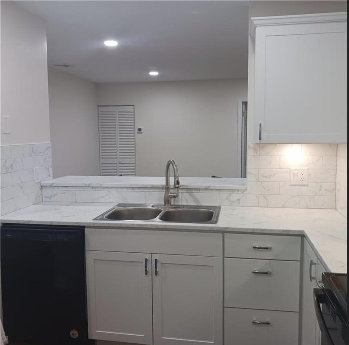 A kitchen sink area features white cabinets, marble-look countertops, and matching subway tile backsplash — 3689 NW 94th Avenue # 51, Sunrise FL 33351, SUNRISE, FL