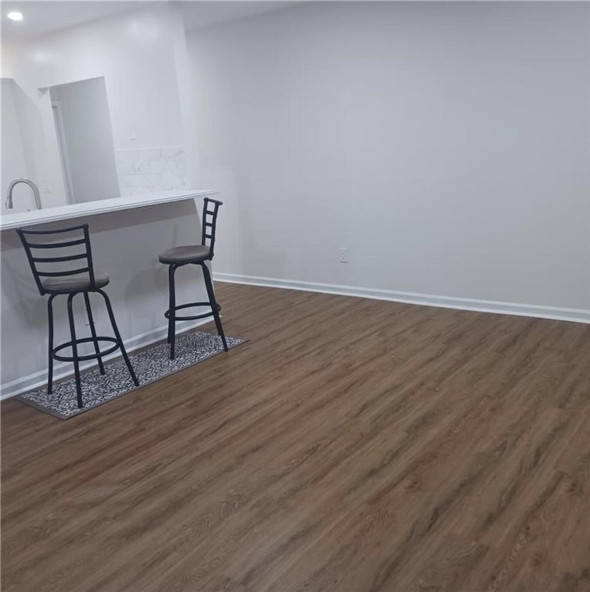 A room with wood-look flooring, light gray walls, and a kitchen counter with two stools — 3689 NW 94th Avenue # 51, Sunrise FL 33351, SUNRISE, FL