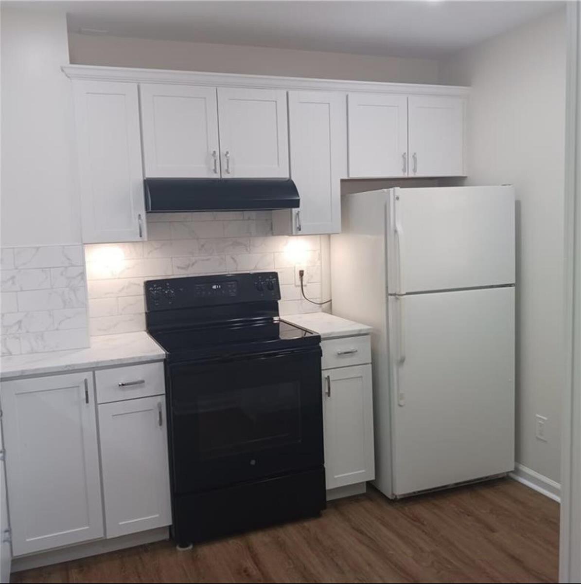 A kitchen features white cabinets, marble-look countertops, a black stove, and a white refrigerator — 3689 NW 94th Avenue # 51, Sunrise FL 33351, SUNRISE, FL