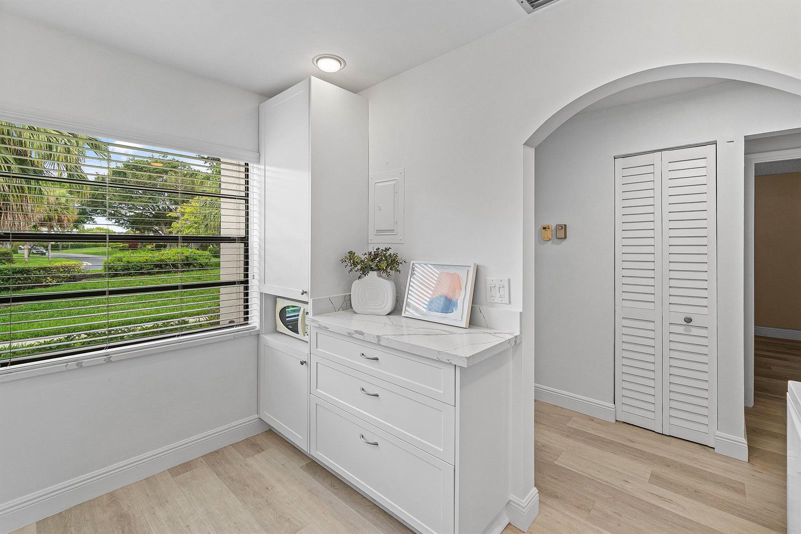 A white cabinet with a marble countertop sits beside a window overlooking a green lawn — 21506 Juego Circle # 28e, Boca Raton FL 33433, BOCA RATON, FL