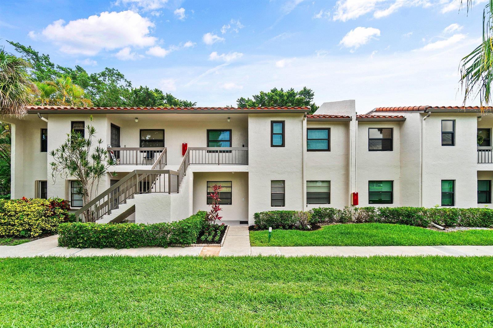 A two-story apartment building with a staircase, balconies, and a landscaped lawn in front — 21506 Juego Circle # 28e, Boca Raton FL 33433, BOCA RATON, FL