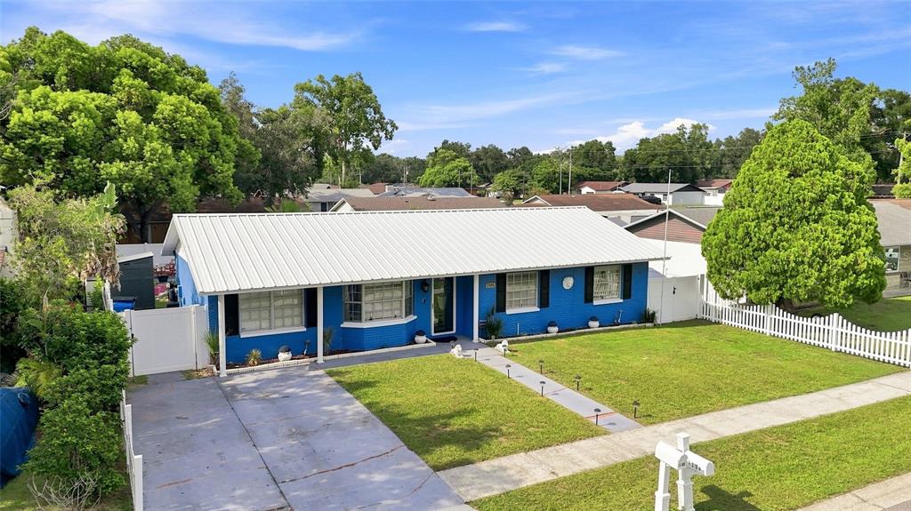 A blue, single-story house with a white metal roof and a front lawn — 1206 TULIPWOOD DRIVE, SEFFNER, FL