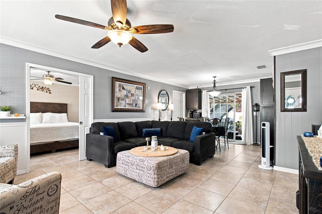 A living room features a dark sectional sofa, a patterned ottoman, and tile flooring — 1206 TULIPWOOD DRIVE, SEFFNER, FL