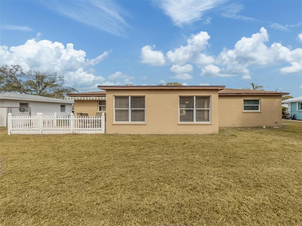 The exterior of a tan, single-story house features a white picket fence and grassy yard — 1215 MANGO AVENUE, VENICE, FL