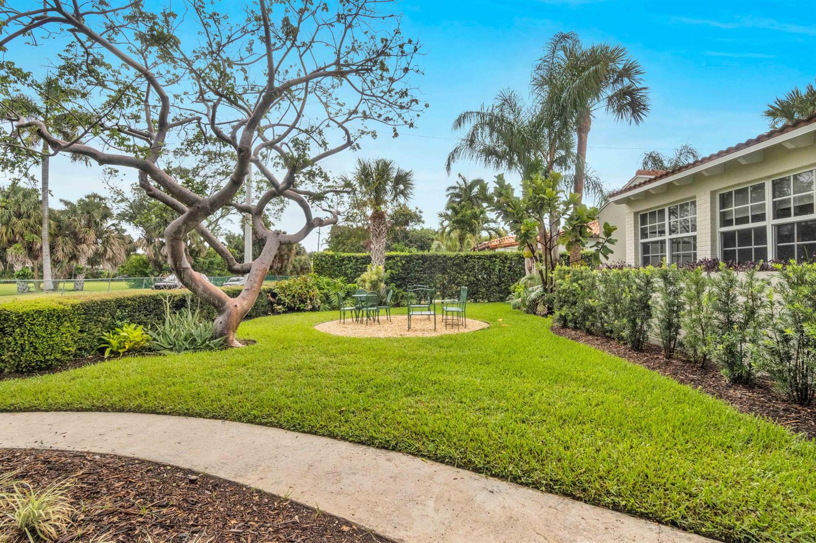 A grassy backyard features a gravel patio area with a table and chairs near trees — 1219 N Lakeside Drive, FL 33460, FL
