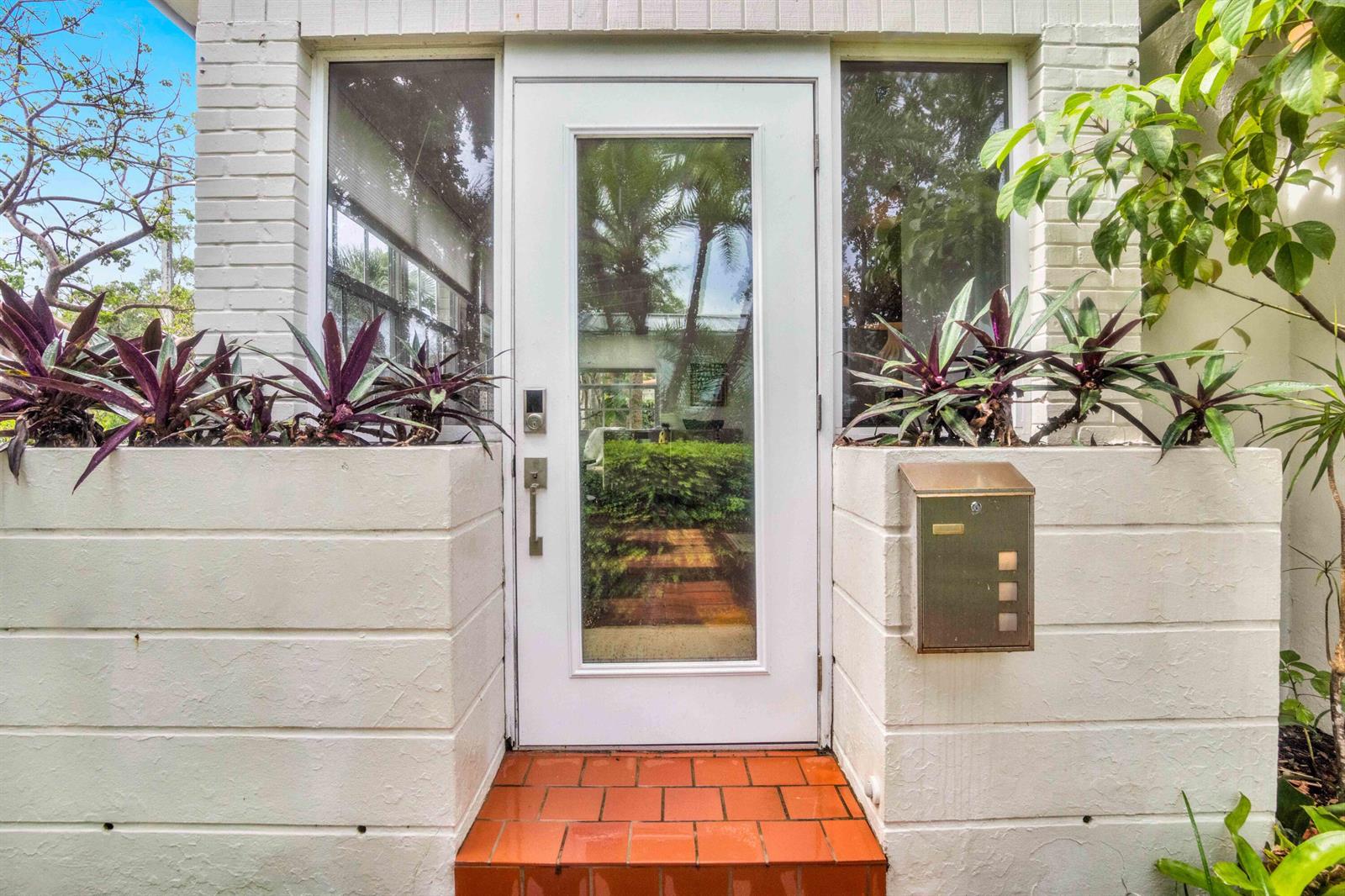 A white front door with a glass panel is flanked by planters and brick steps — 1219 N Lakeside Drive, FL 33460, FL