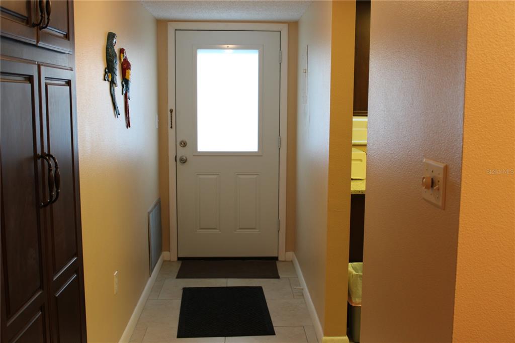 An entryway features a white door with a glass panel, tile flooring, and dark cabinetry — 325 N CAUSEWAY UNIT D108, NEW SMYRNA BEACH, FL