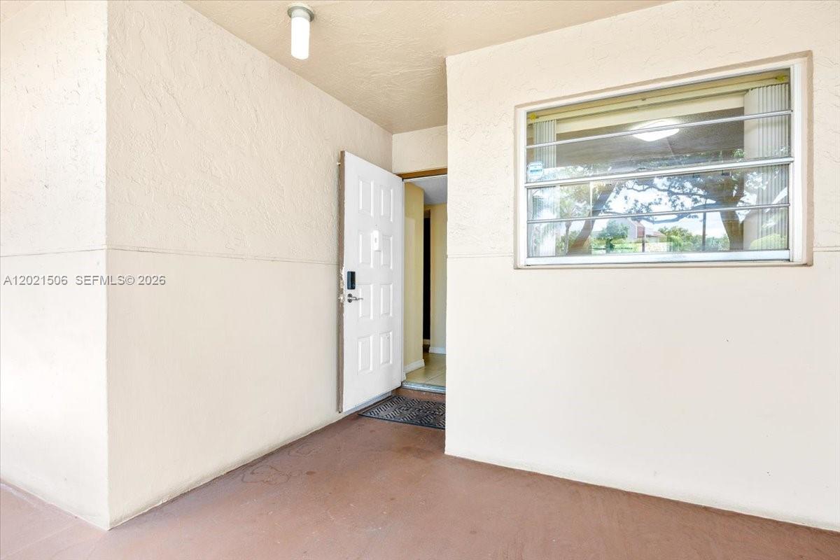 A covered entryway features a white door, a single window, and light-colored stucco walls — 9501 Seagrape Dr # 102, Davie FL 33324, DAVIE, FL