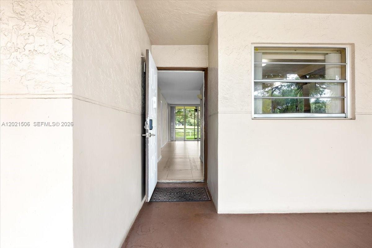 An open front door reveals a tiled hallway leading to a screened-in patio — 9501 Seagrape Dr # 102, Davie FL 33324, DAVIE, FL