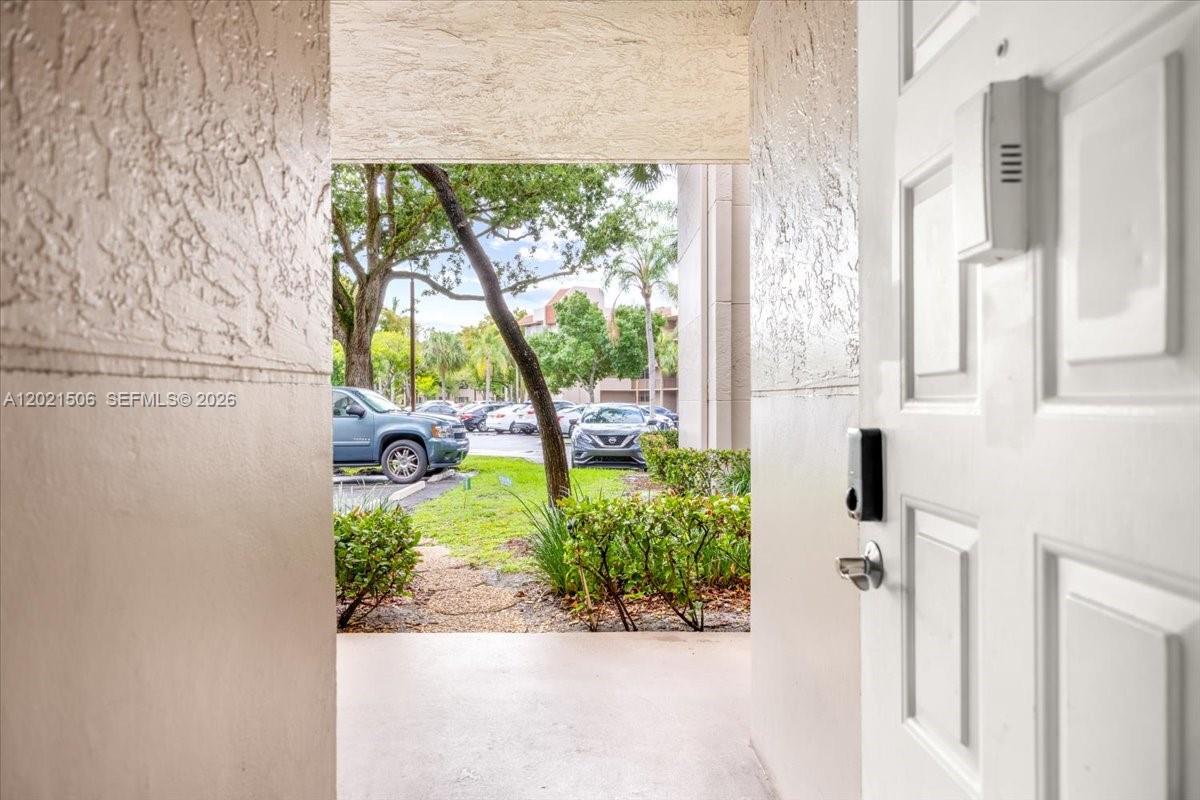 A view from an entryway looking out toward a parking lot with trees — 9501 Seagrape Dr # 102, Davie FL 33324, DAVIE, FL