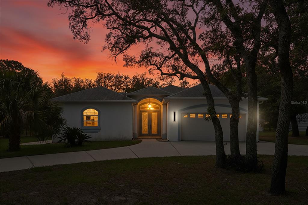 A single-story house with a garage and arched entryway at sunset — 12408 KANAWHA DRIVE, WEEKI WACHEE, FL