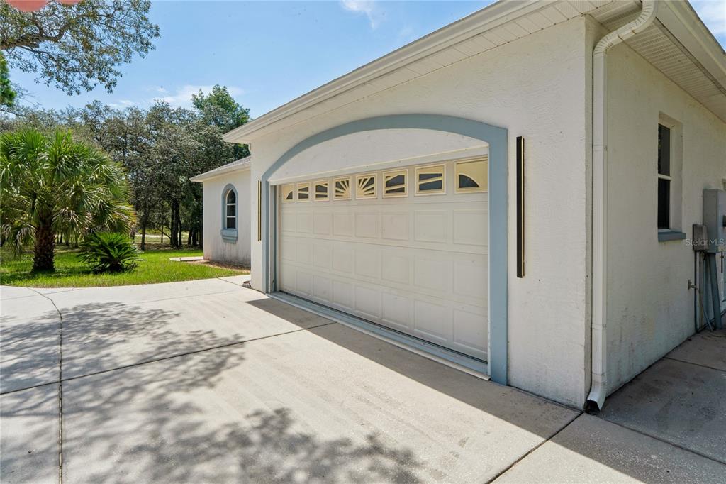 A white garage with a blue arched frame and windows sits beside a concrete driveway — 12408 KANAWHA DRIVE, WEEKI WACHEE, FL