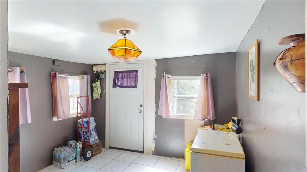 A room with gray walls, white tile flooring, a stained-glass light fixture, and a door — 5651 6TH STREET, ZEPHYRHILLS, FL