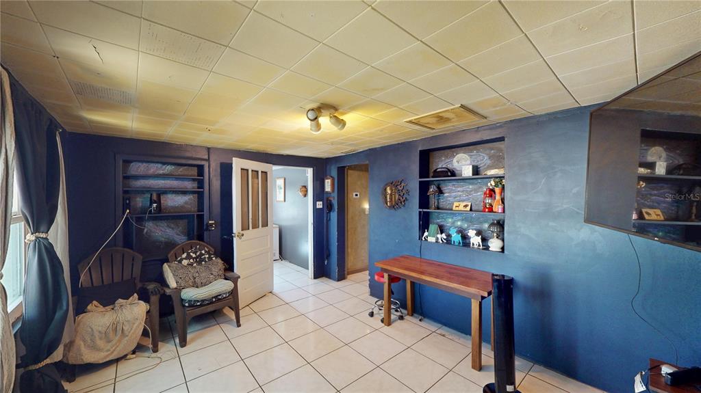 A room with blue walls, tiled floors, built-in shelving, and a drop ceiling — 5651 6TH STREET, ZEPHYRHILLS, FL