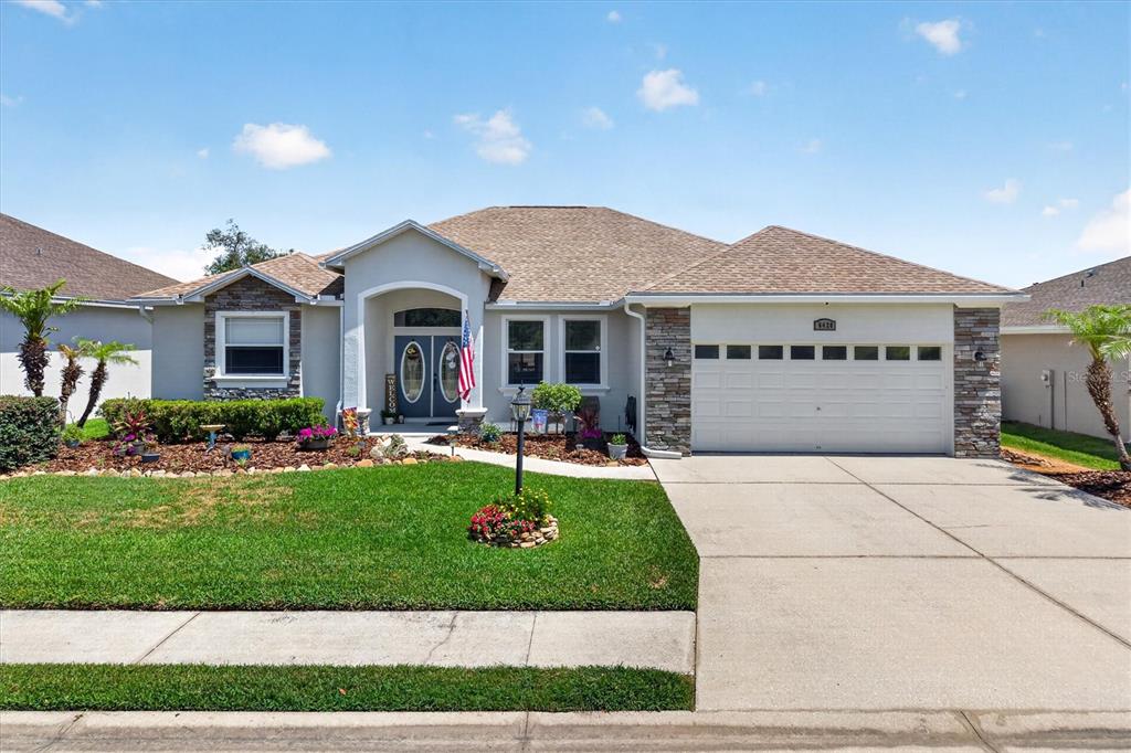 A single-story suburban house with a stone-accented facade, a two-car garage, and a landscaped yard — 6420 EVERGREEN PARK DRIVE, LAKELAND, FL