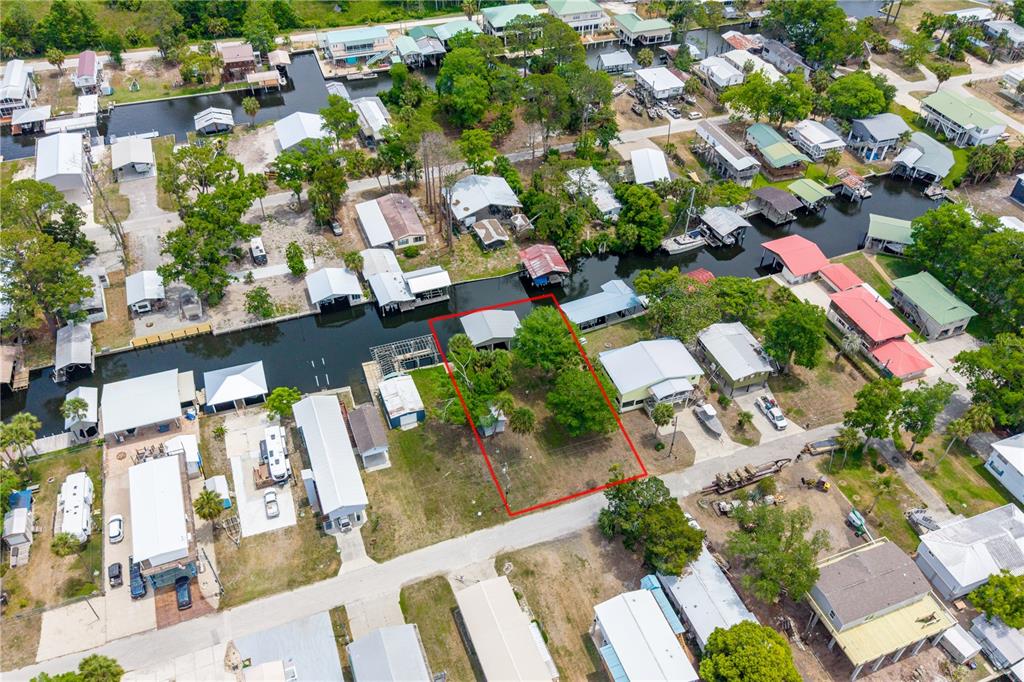 An aerial view shows a vacant, rectangular lot outlined in red near a canal — 75 NE 236TH STREET, SUWANNEE, FL