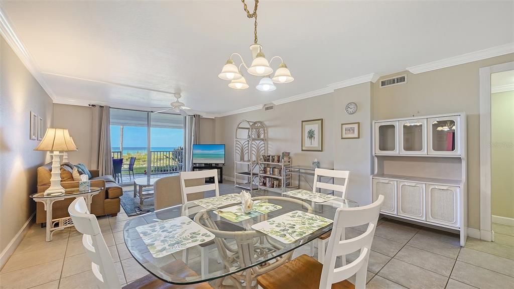 A dining area with a glass table and chairs overlooks a living room and ocean view — 4325 GULF OF MEXICO DRIVE UNIT 103, LONGBOAT KEY, FL