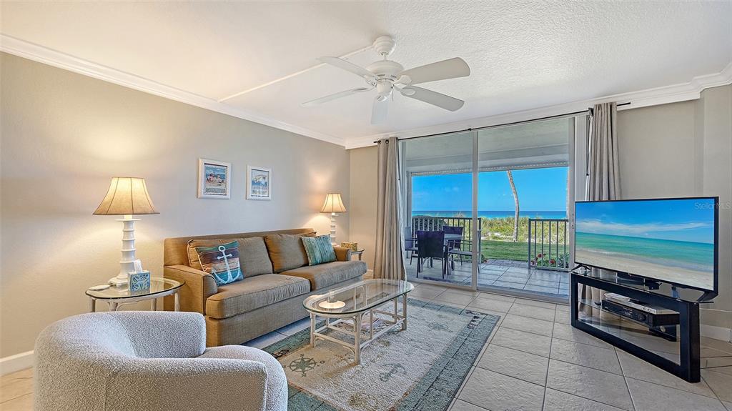 A living room features a sofa, armchair, glass coffee table, and sliding doors to a patio — 4325 GULF OF MEXICO DRIVE UNIT 103, LONGBOAT KEY, FL