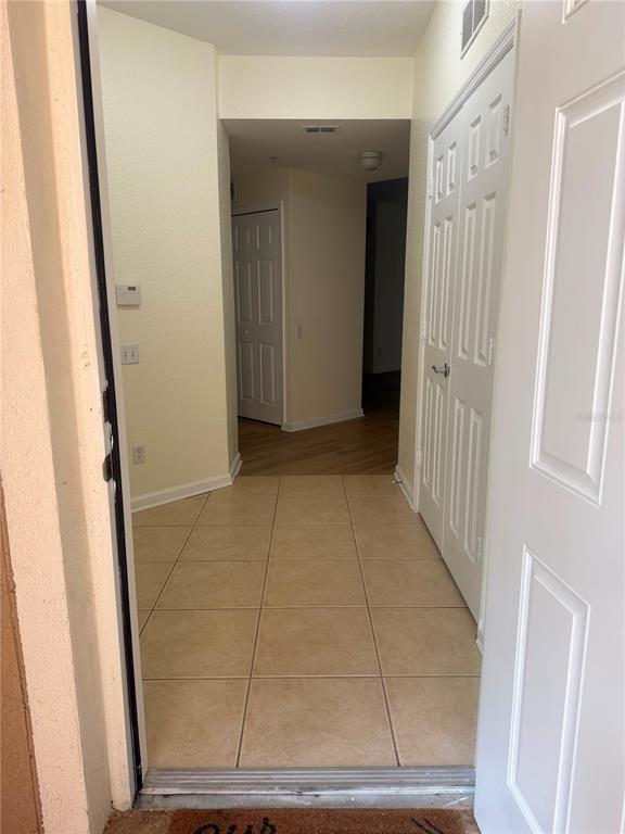 An entryway with tile flooring leads to a hallway with wood-look floors and white doors — 2525 SAN TECLA STREET UNIT 106, ORLANDO, FL