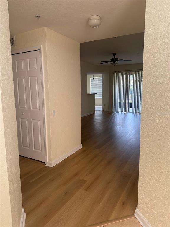 An entryway with light wood-look flooring leads into an open living area with a ceiling fan — 2525 SAN TECLA STREET UNIT 106, ORLANDO, FL