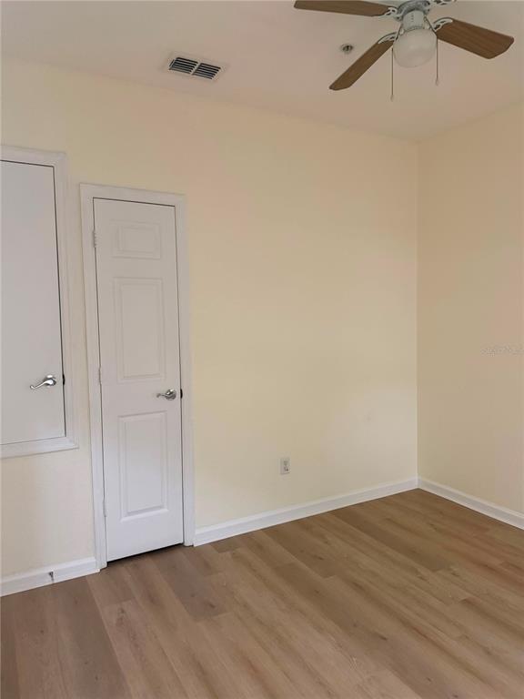 An empty room with light-colored walls, wood-look flooring, a ceiling fan, and two white doors — 2525 SAN TECLA STREET UNIT 106, ORLANDO, FL