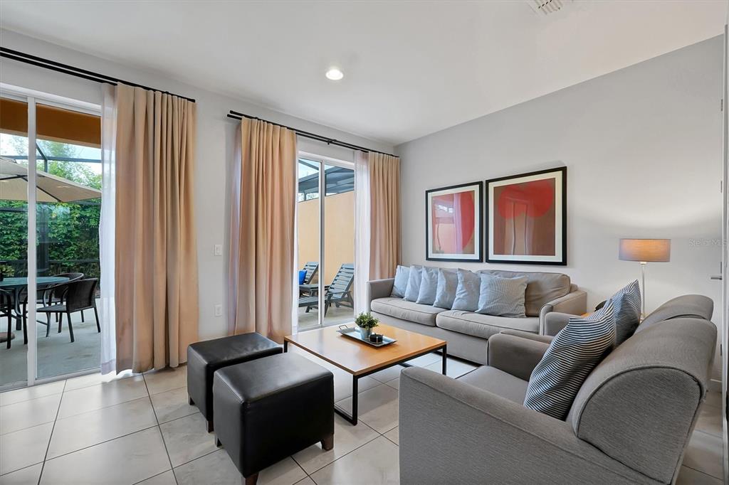 A living room features gray sofas, a wooden coffee table, and sliding glass doors to a patio — 2628 ROADSTER LANE, KISSIMMEE, FL