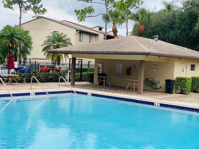 A swimming pool sits in front of a covered outdoor pavilion with tables and chairs — 202 Foxtail Drive # F1, FL 33415, FL