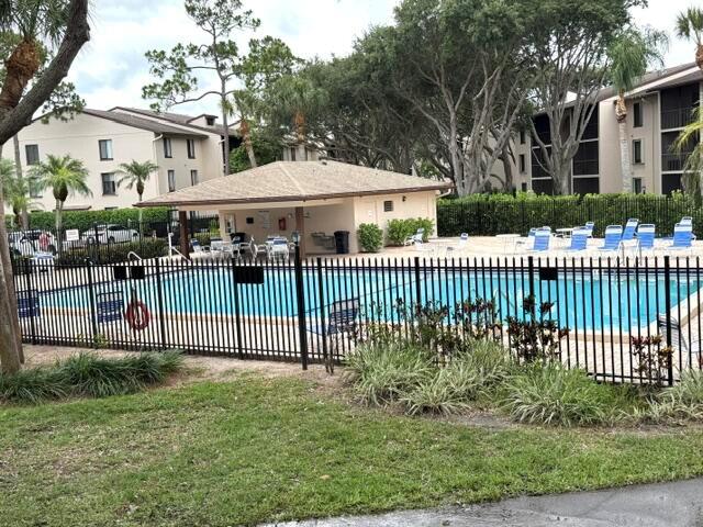 A swimming pool with a covered pavilion is enclosed by a black metal fence — 202 Foxtail Drive # F1, FL 33415, FL