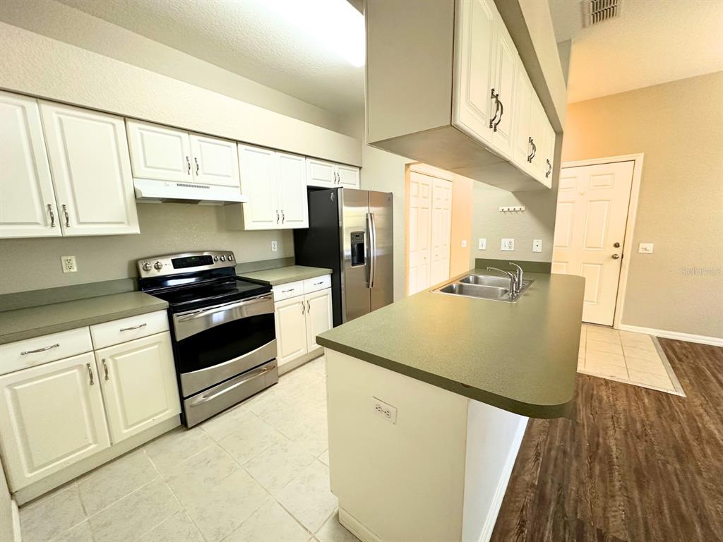 A kitchen features white cabinetry, green countertops, stainless steel appliances, and a central island — 1005 EAGLE POND DRIVE UNIT 1005, WINTER HAVEN, FL