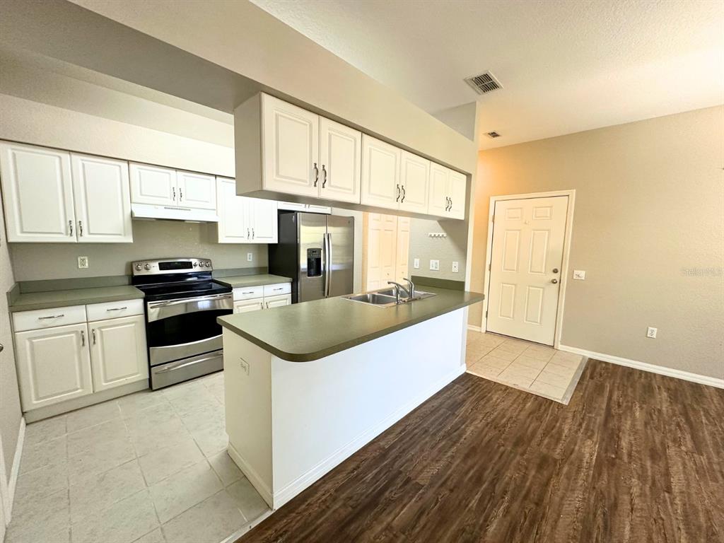 A kitchen with white cabinets, stainless steel appliances, and a green countertop island — 1005 EAGLE POND DRIVE UNIT 1005, WINTER HAVEN, FL