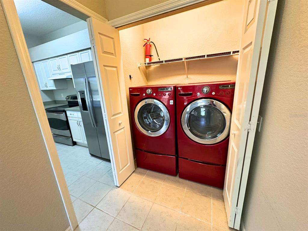 A laundry closet with red appliances sits next to a kitchen with white cabinets — 1005 EAGLE POND DRIVE UNIT 1005, WINTER HAVEN, FL