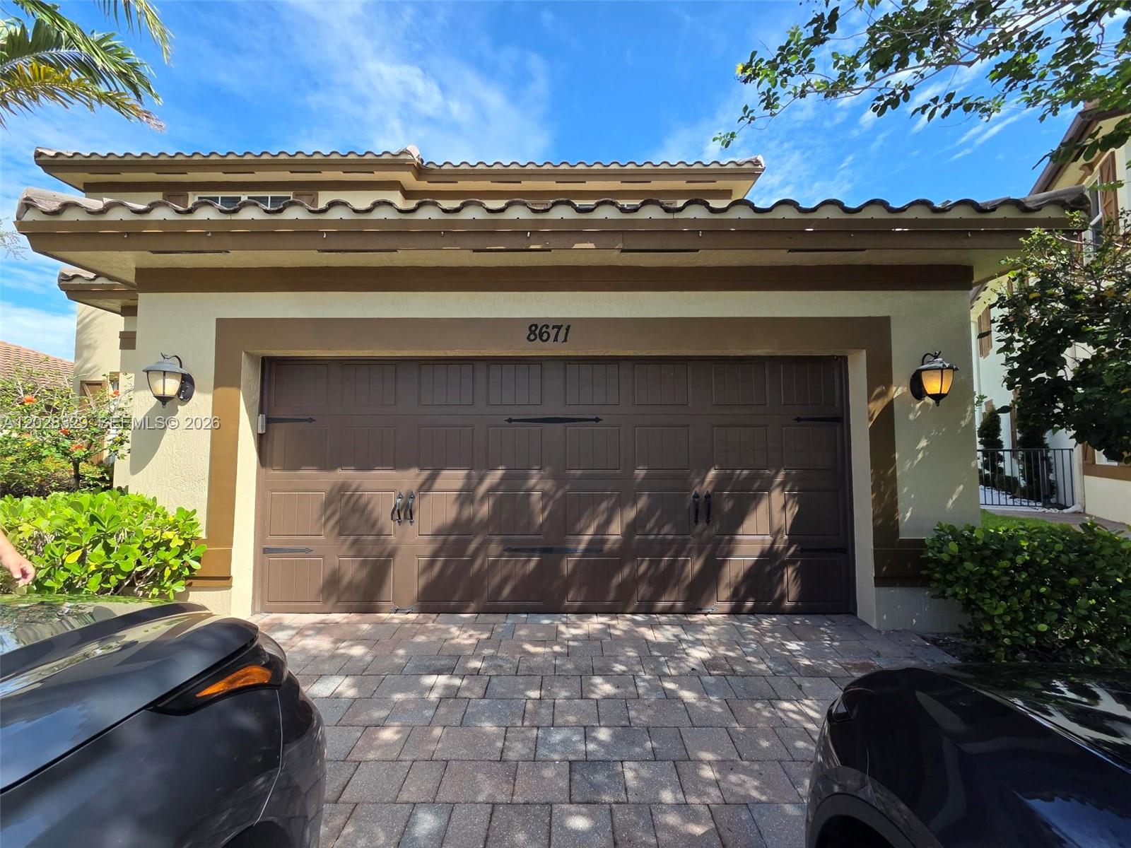 A brown garage door with decorative hardware is centered on the exterior of a house — 8671 Lakeside Bnd # 1, Parkland FL 33076, PARKLAND, FL
