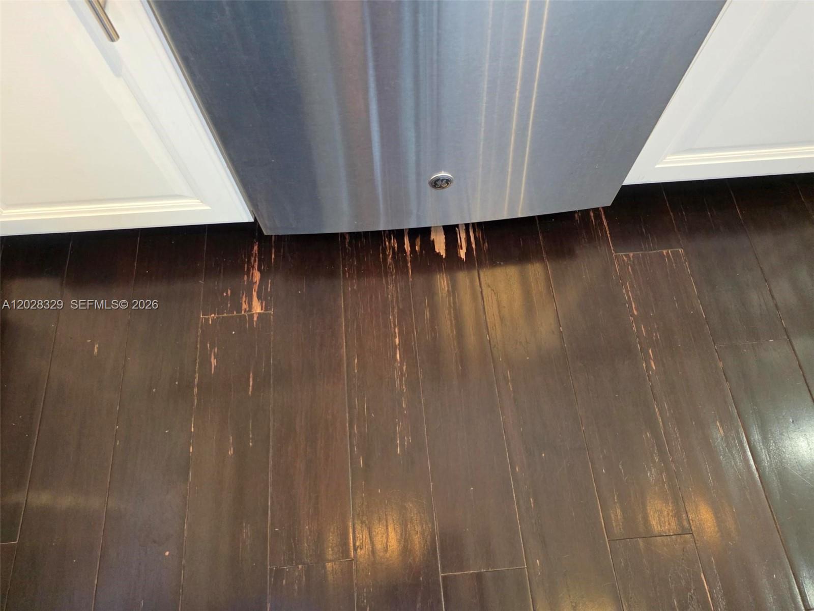 A stainless steel dishwasher sits above damaged dark wood flooring in a kitchen — 8671 Lakeside Bnd # 1, Parkland FL 33076, PARKLAND, FL