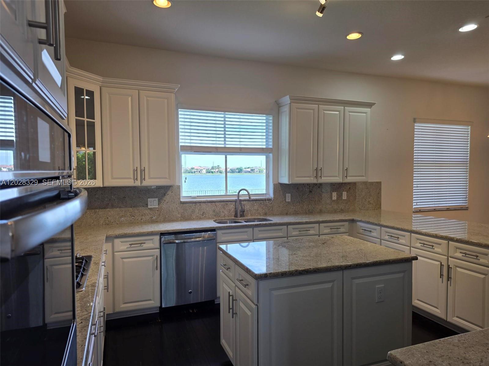 A kitchen features white cabinetry, granite countertops, stainless steel appliances, and a water view — 8671 Lakeside Bnd # 1, Parkland FL 33076, PARKLAND, FL