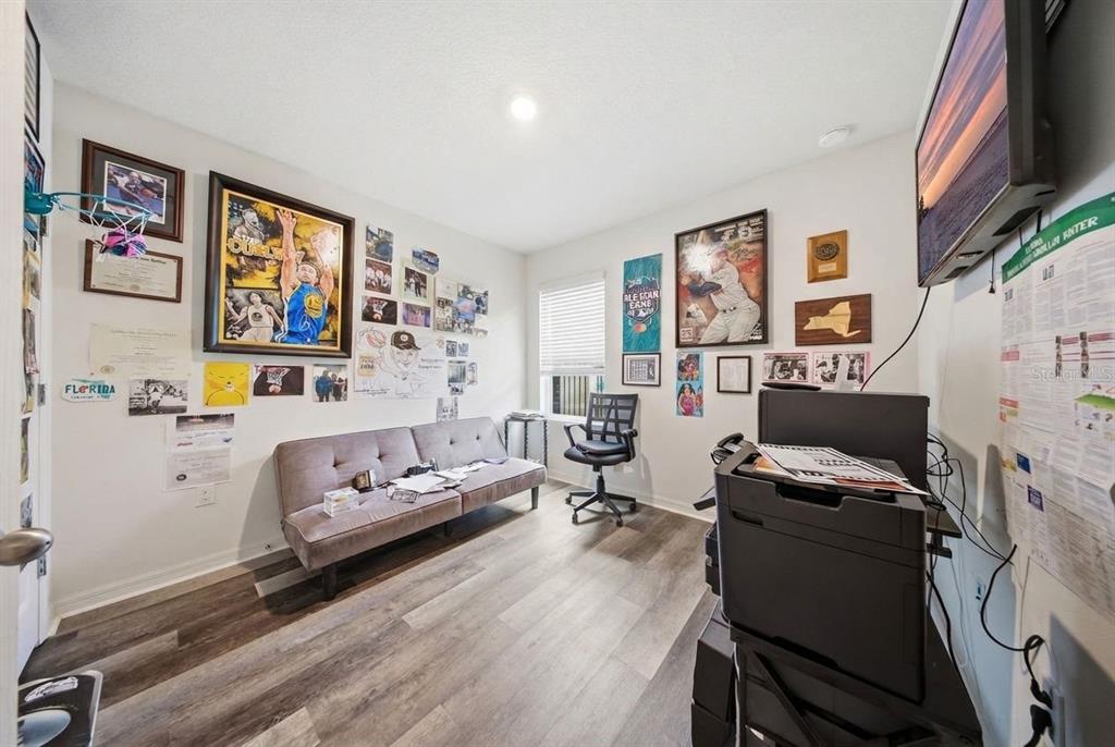 A home office features a gray futon, a desk chair, a printer, and sports-themed wall decor — 209 MEGHAN CIR, DELAND, FL