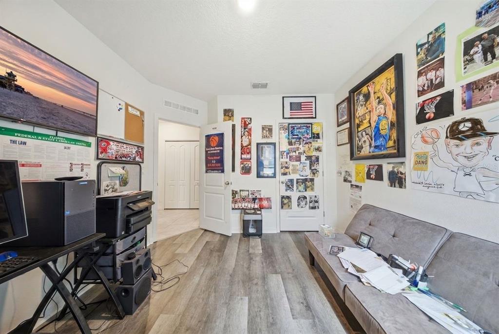 A home office with wood-look flooring, a desk, a sofa, and walls decorated with sports memorabilia — 209 MEGHAN CIR, DELAND, FL