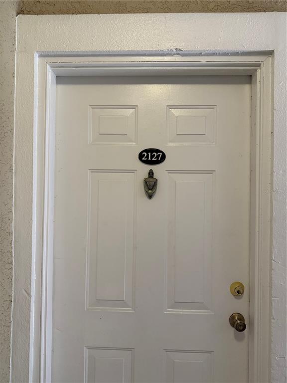 A white front door features a black oval address plaque, a door knocker, and hardware — 3725 CONROY ROAD UNIT 2127, ORLANDO, FL