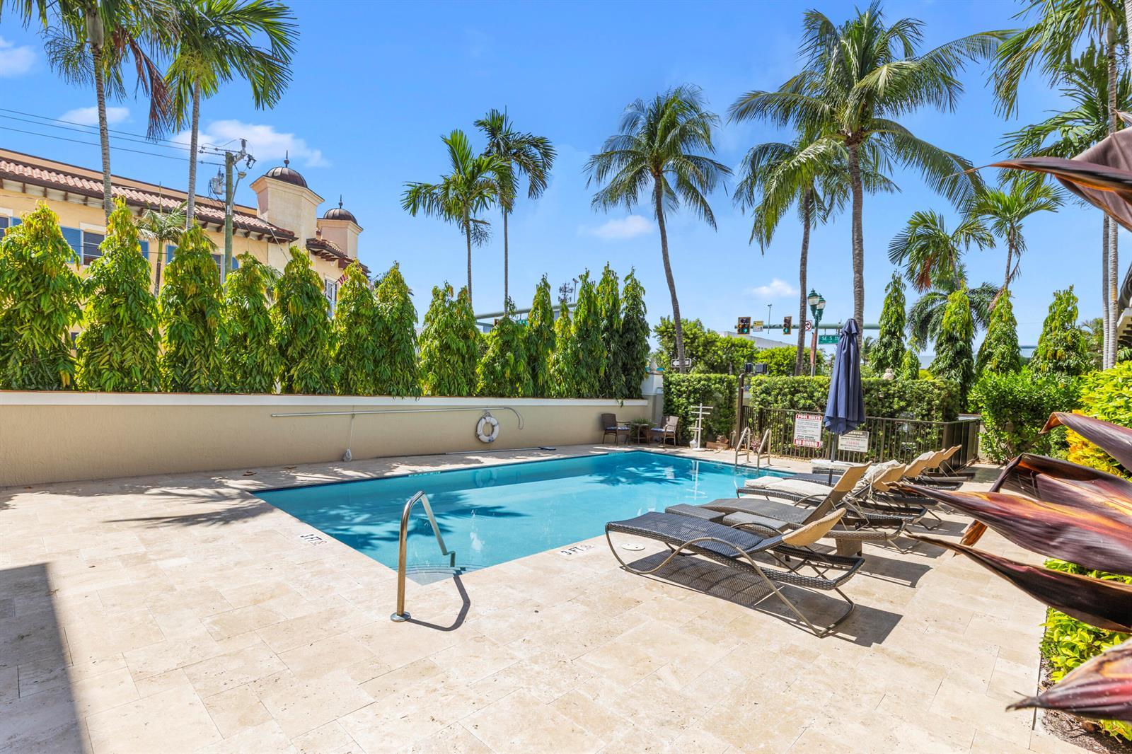 An outdoor swimming pool surrounded by lounge chairs, palm trees, and a privacy hedge — 65 SE 5th Avenue, Delray Beach FL 33483, DELRAY BEACH, FL