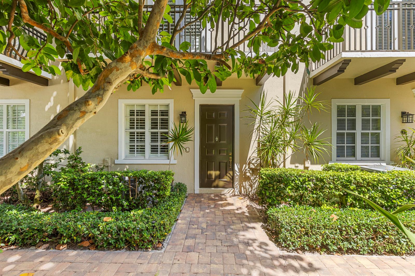A brown front door is centered between two windows on a beige townhouse exterior — 65 SE 5th Avenue, Delray Beach FL 33483, DELRAY BEACH, FL