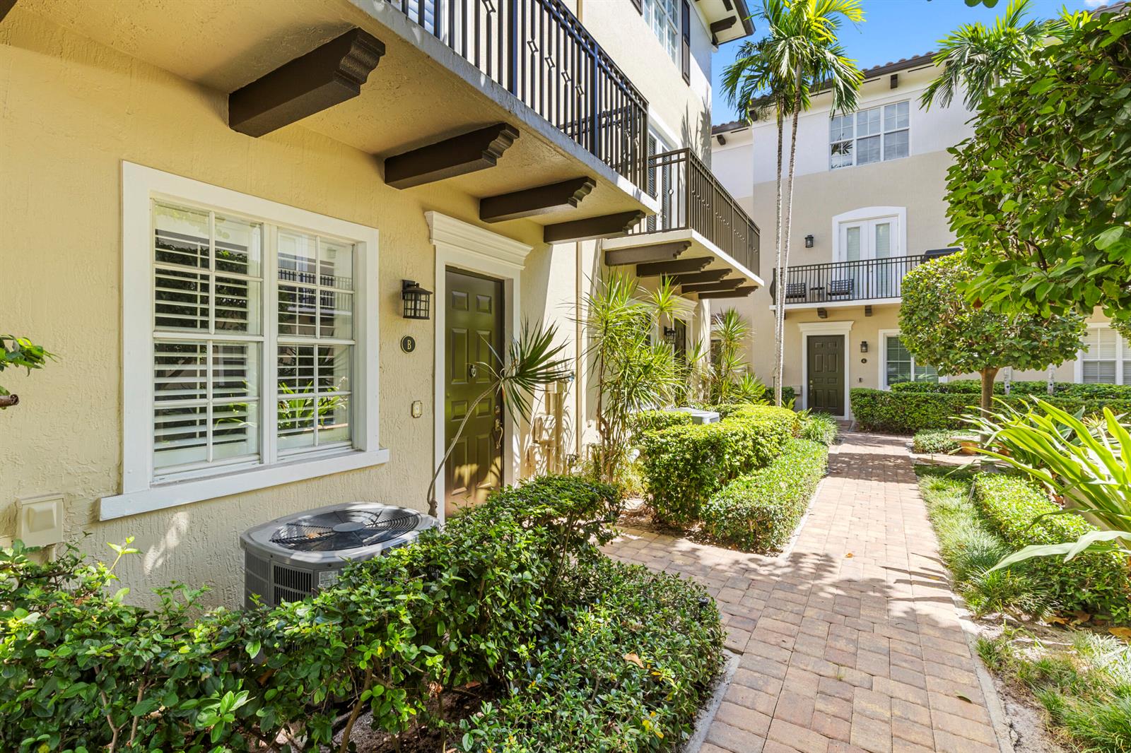 A paved walkway leads to the entrances of two multi-story townhomes with balconies and landscaping — 65 SE 5th Avenue, Delray Beach FL 33483, DELRAY BEACH, FL
