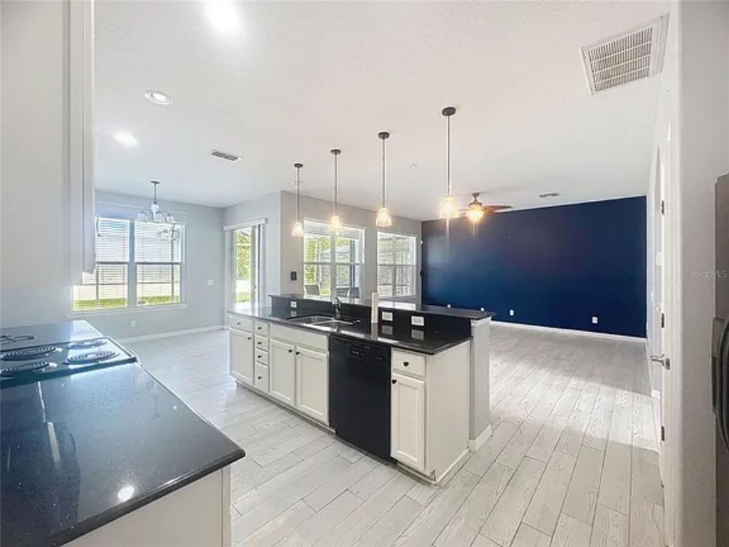 A kitchen with white cabinets, black countertops, and a dark blue accent wall in back — 1476 LEXINGTON AVE, DAVENPORT, FL