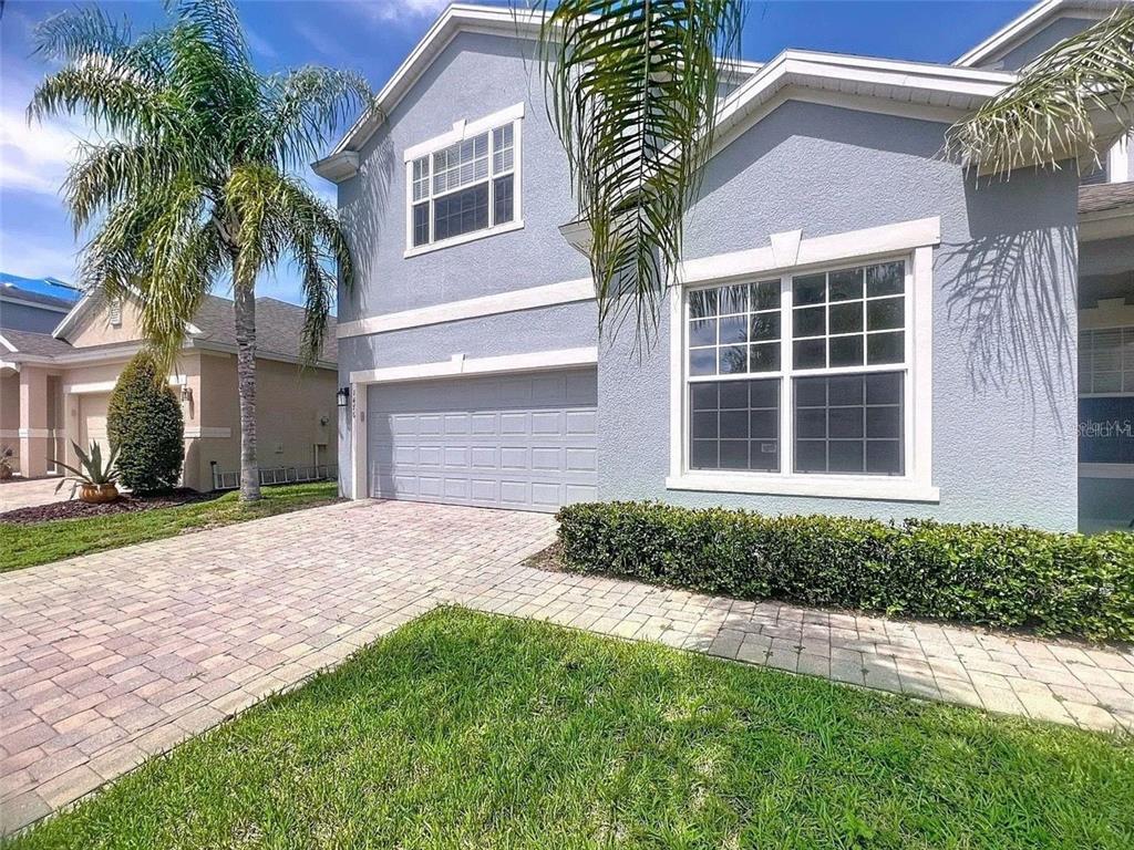 A two-story house with a light blue stucco exterior, a garage, and a paved driveway — 1476 LEXINGTON AVE, DAVENPORT, FL