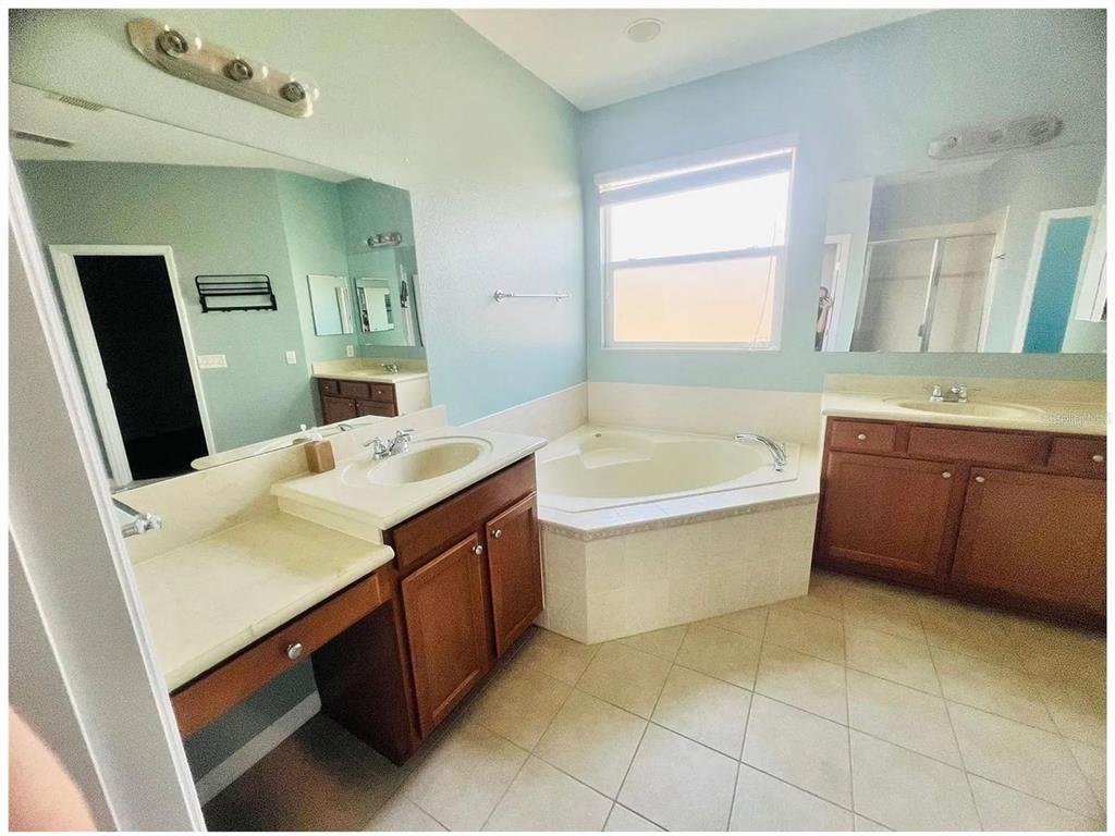 A bathroom features light blue walls, two wood vanities, and a corner soaking tub — 1476 LEXINGTON AVE, DAVENPORT, FL