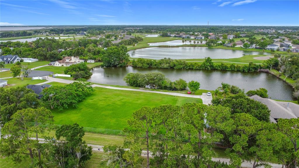 An aerial view shows a vacant grassy lot situated next to a pond and neighborhood homes — 2959 MONICA TERRACE, KISSIMMEE, FL
