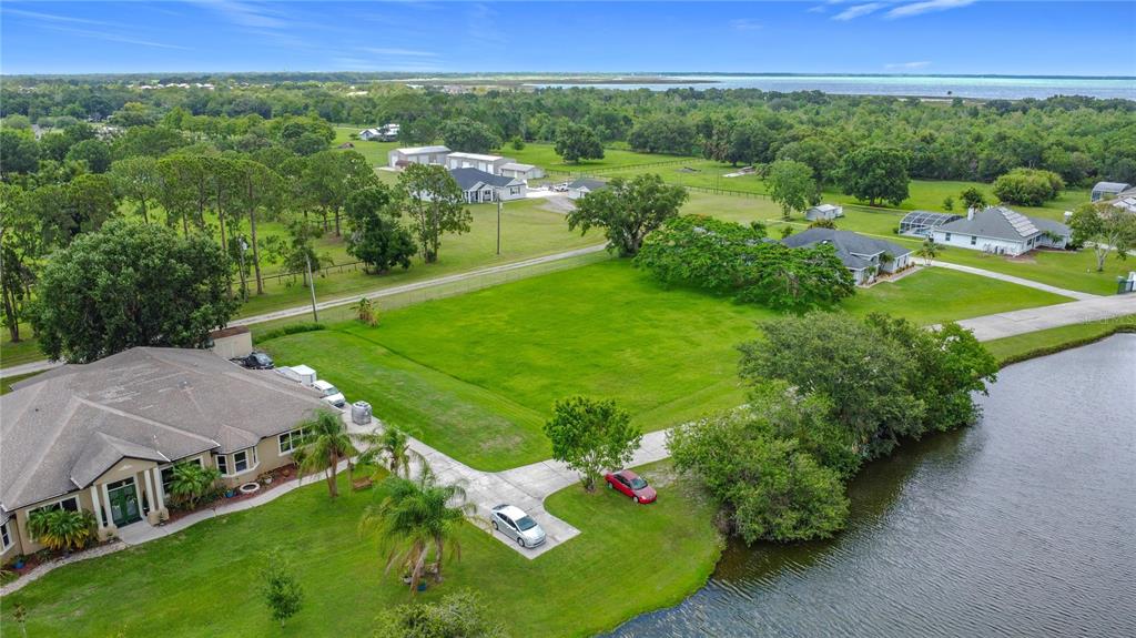An aerial view shows a house with a large grassy yard next to a lake — 2959 MONICA TERRACE, KISSIMMEE, FL