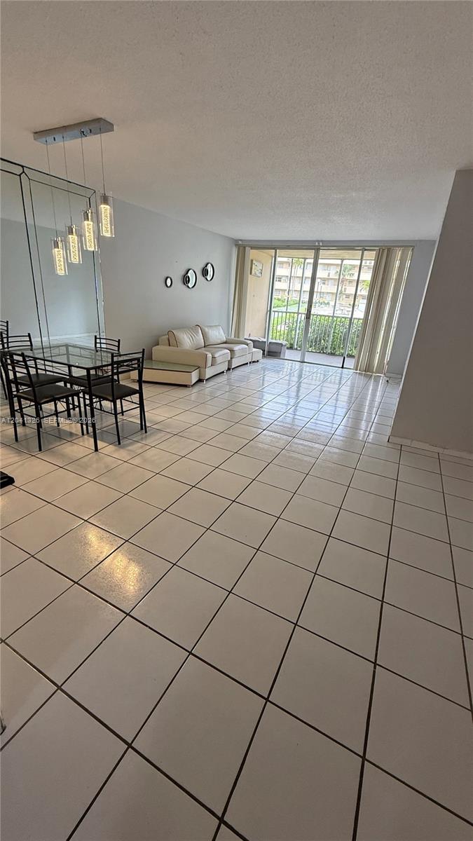 A living and dining area features white tile flooring, a glass dining table, and a balcony — 1770 NE 191st St # 1, Miami FL 33179, MIAMI, FL