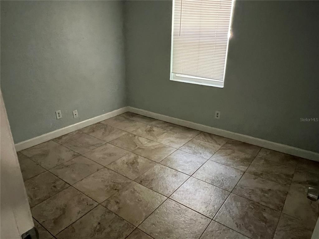 A bedroom features light gray walls, a single window with blinds, and tan tiled flooring — 920 MAYDELL DRIVE UNIT B, TAMPA, FL