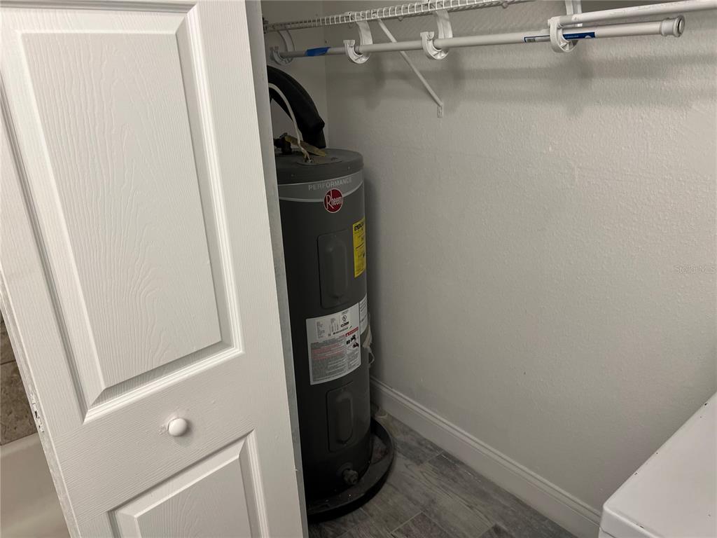 A Rheem water heater sits inside a closet with white shelving and gray flooring — 920 MAYDELL DRIVE UNIT B, TAMPA, FL