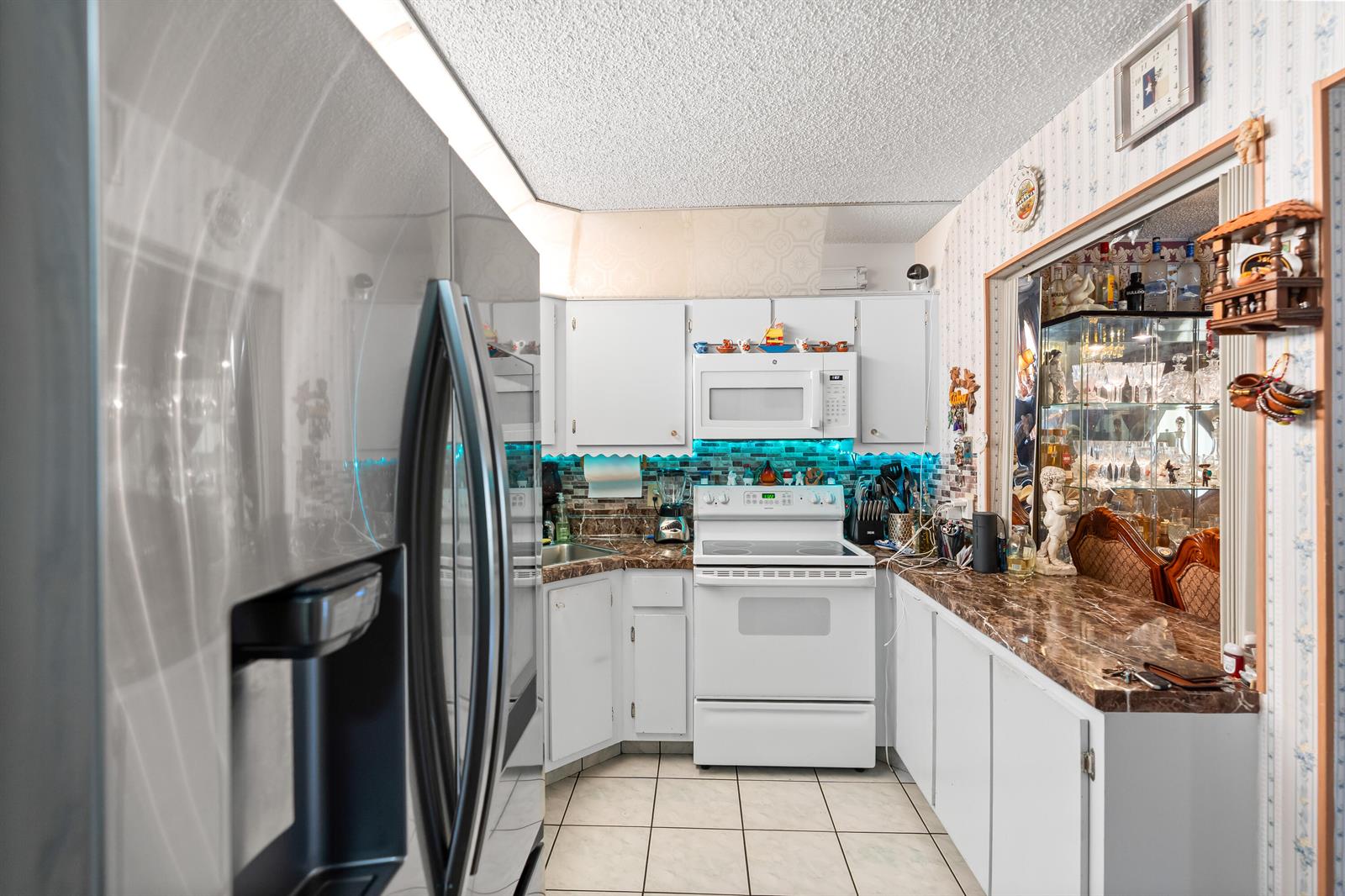 A kitchen features white cabinets, a white stove, a microwave, and brown marble-patterned countertops — 4996 Sable Pine Circle # A1, West Palm Beach FL 33417, WEST PALM BEACH, FL